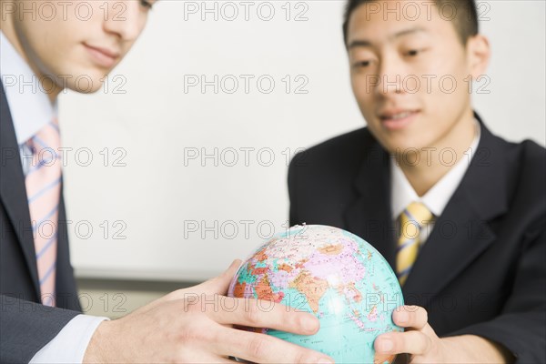 Businessmen looking at small globe