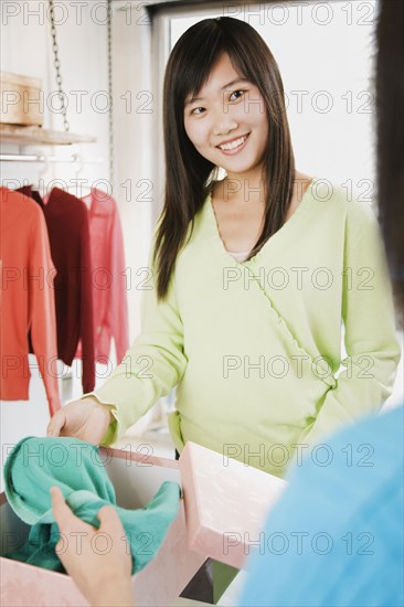 Chinese woman boxing clothing at store counter