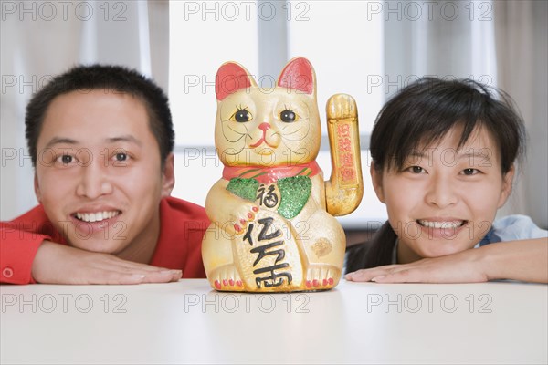 Chinese couple smiling next to cat figurine