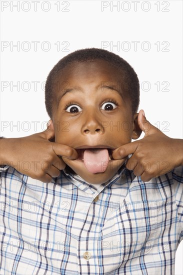 Mixed race boy making a face with tongue out