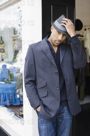 African American man standing in shop doorway with fedora