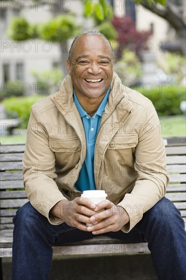 Mixed race man drinking coffee in park