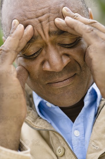 Grimacing mixed race man rubbing forehead