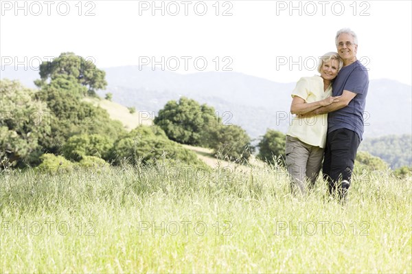 Caucasian couple hugging in field