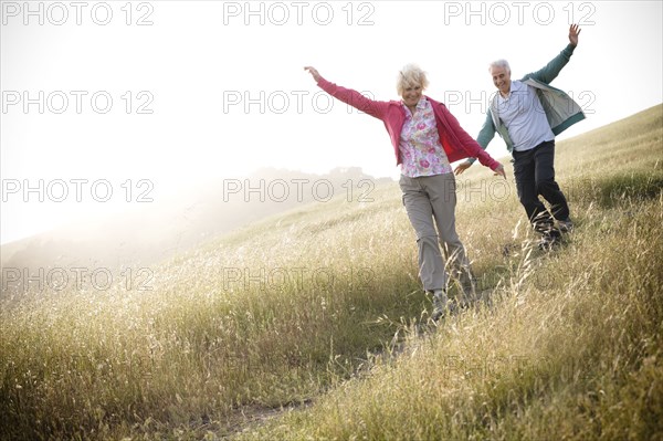 Caucasian couple running down hill