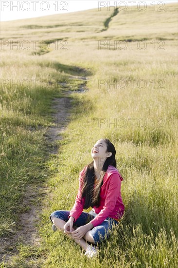 Hispanic girl sitting in field laughing