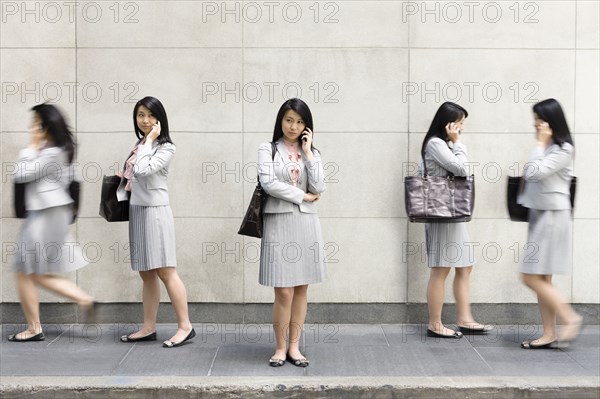 Multiple-exposure of Chinese businesswoman talking on cell phone