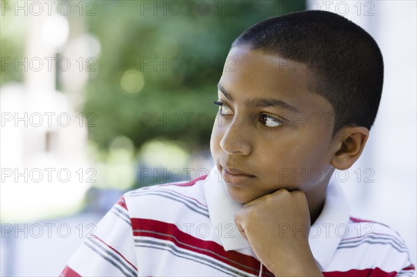 Serious mixed race boy with hand on chin