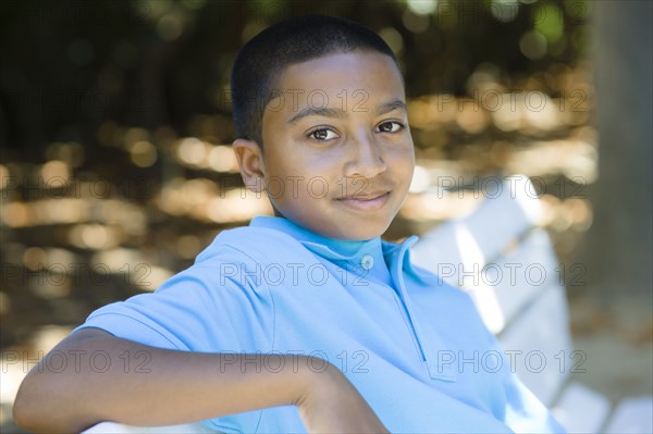 Smiling mixed race boy sitting in park