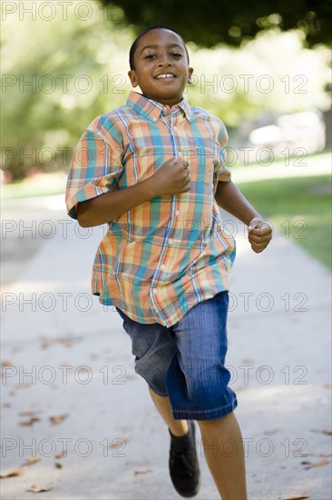 Mixed race boy running on sidewalk