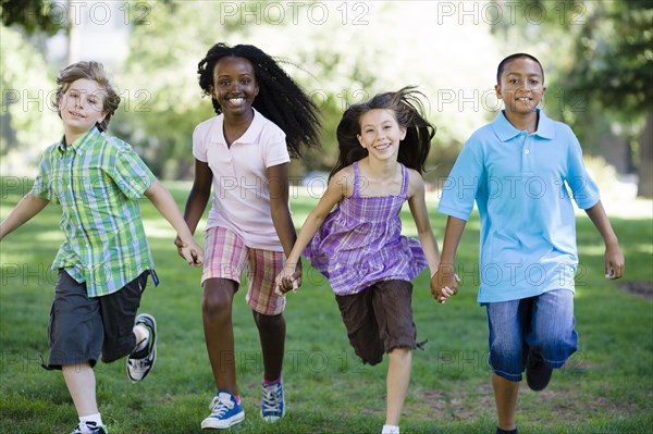 Happy children holding hands and running in park