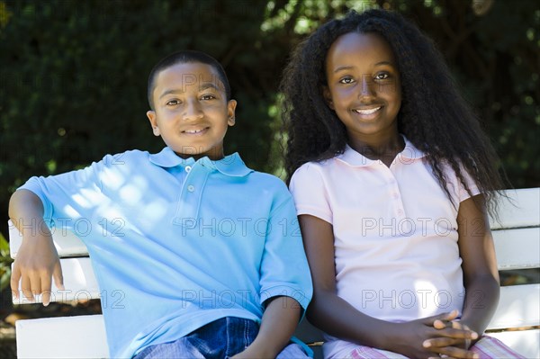 Smiling children sitting on park bench