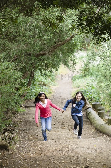 Girls holding hands and running on path