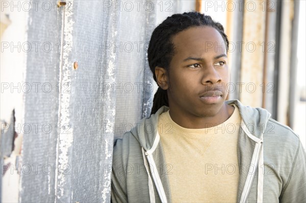 Serious Black man leaning against wall