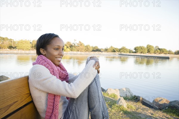 Woman sitting on bench near shore