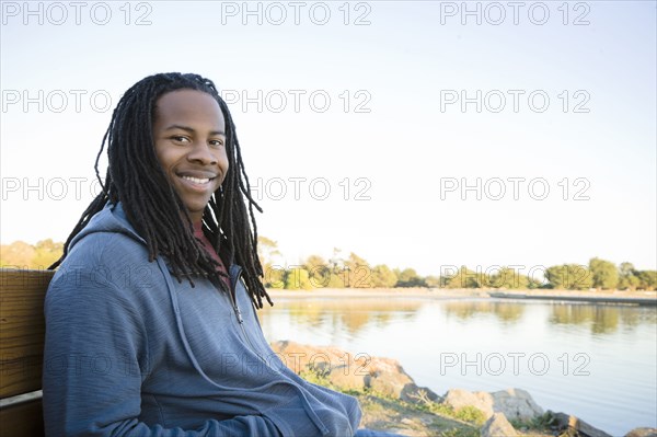 Black man sitting near shore