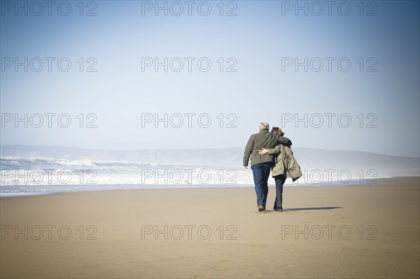 Caucasian couple walking on beach