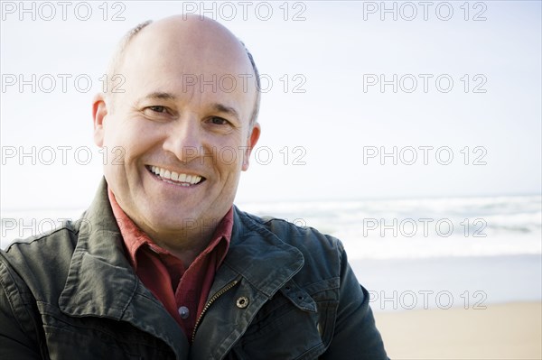 Smiling Caucasian man standing on beach