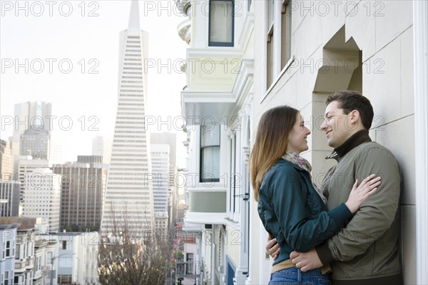 Caucasian couple hugging in city