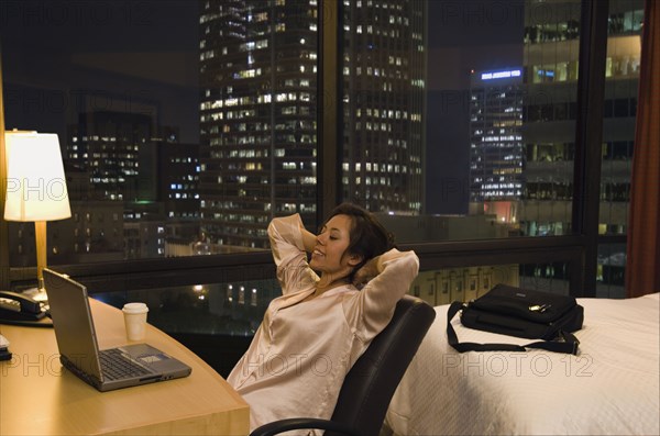 Hispanic woman looking at laptop in hotel room