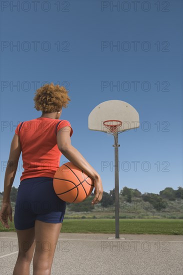 African woman holding basketball on court