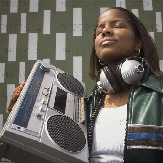 Low angle view of African woman listening to music on portable stereo