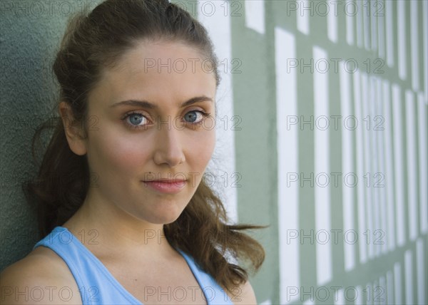 Close up of young woman leaning against wall