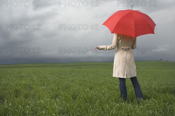 Rear view of woman holding umbrella in field