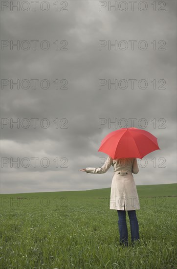 Rear view of woman holding umbrella in field