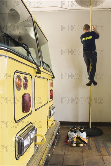 Male firefighter sliding down pole