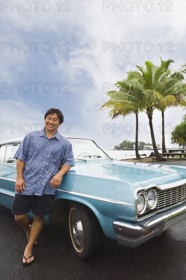 Asian man leaning on car