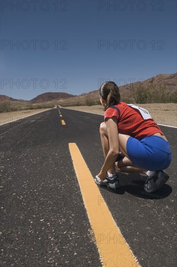 Mixed Race woman tying running shoe