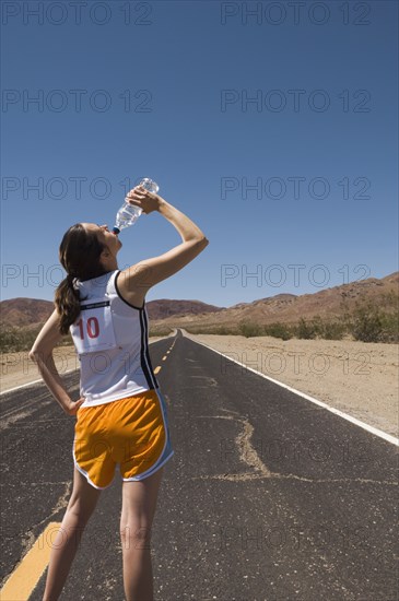 Mixed Race female runner drinking water