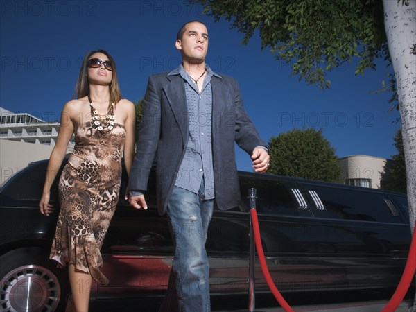 Multi-ethnic couple walking away from limousine