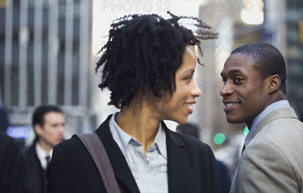 African American businesswoman smiling at businessman on street