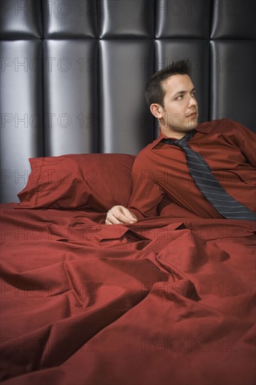 Man wearing shirt and tie on bed