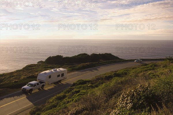 Truck pulling camper on coastal highway