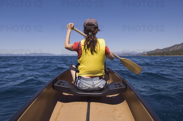 Rear view of woman paddling canoe