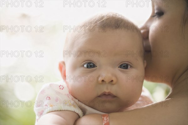 Hispanic baby looking over mother's shoulder