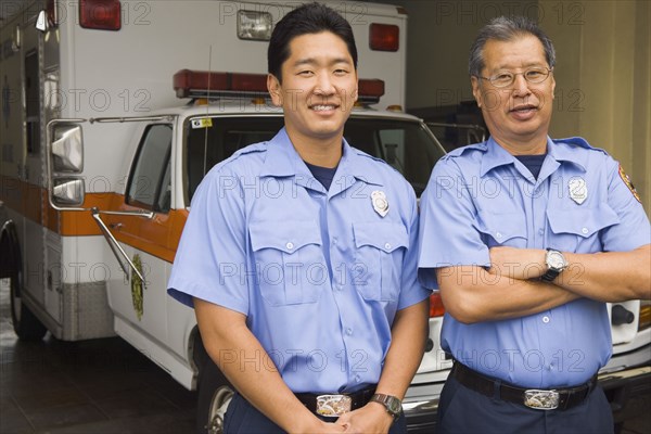 Asian male paramedics in front of ambulance