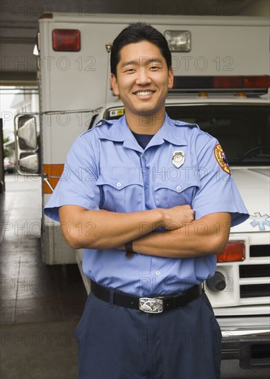 Asian male paramedic in front of ambulance