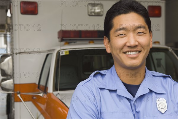 Asian male paramedic in front of ambulance