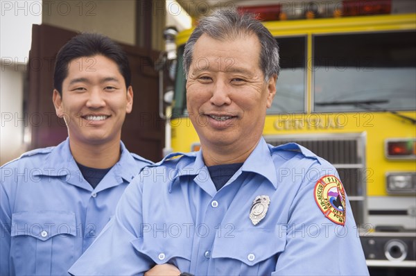 Asian male paramedics in front of ambulance