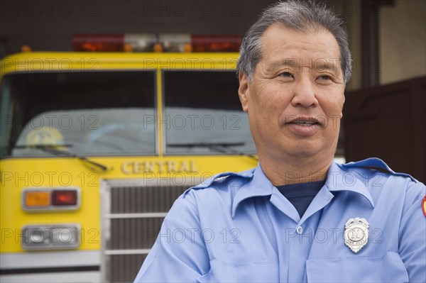 Asian male paramedic in front of ambulance