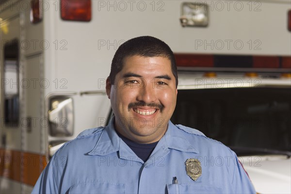 Asian male paramedic in front of ambulance