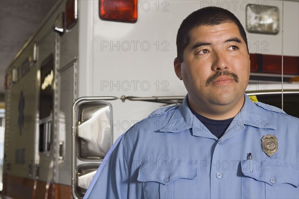 Asian male paramedic in front of ambulance