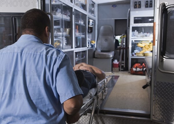 Asian male paramedic loading patient into ambulance