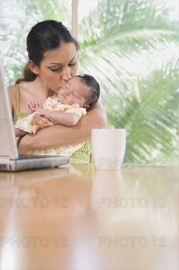 Hispanic mother kissing baby