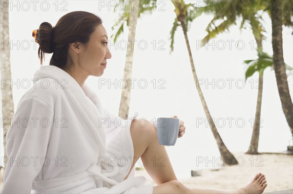 Asian woman in bathrobe holding mug