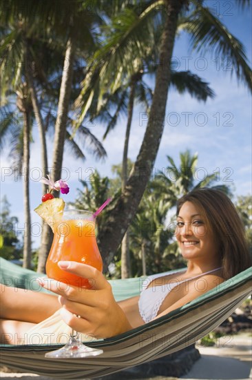 Asian woman with cocktail in hammock